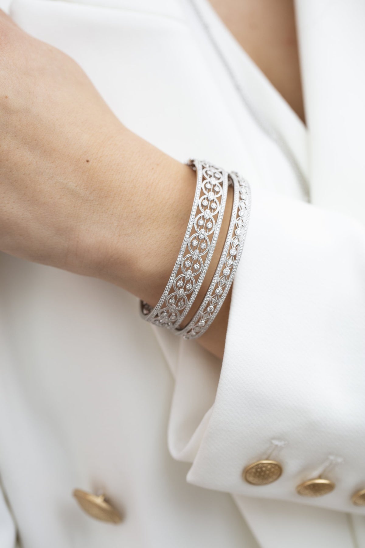 Woman in a white blazer wearing two white gold Heritage diamond bangles