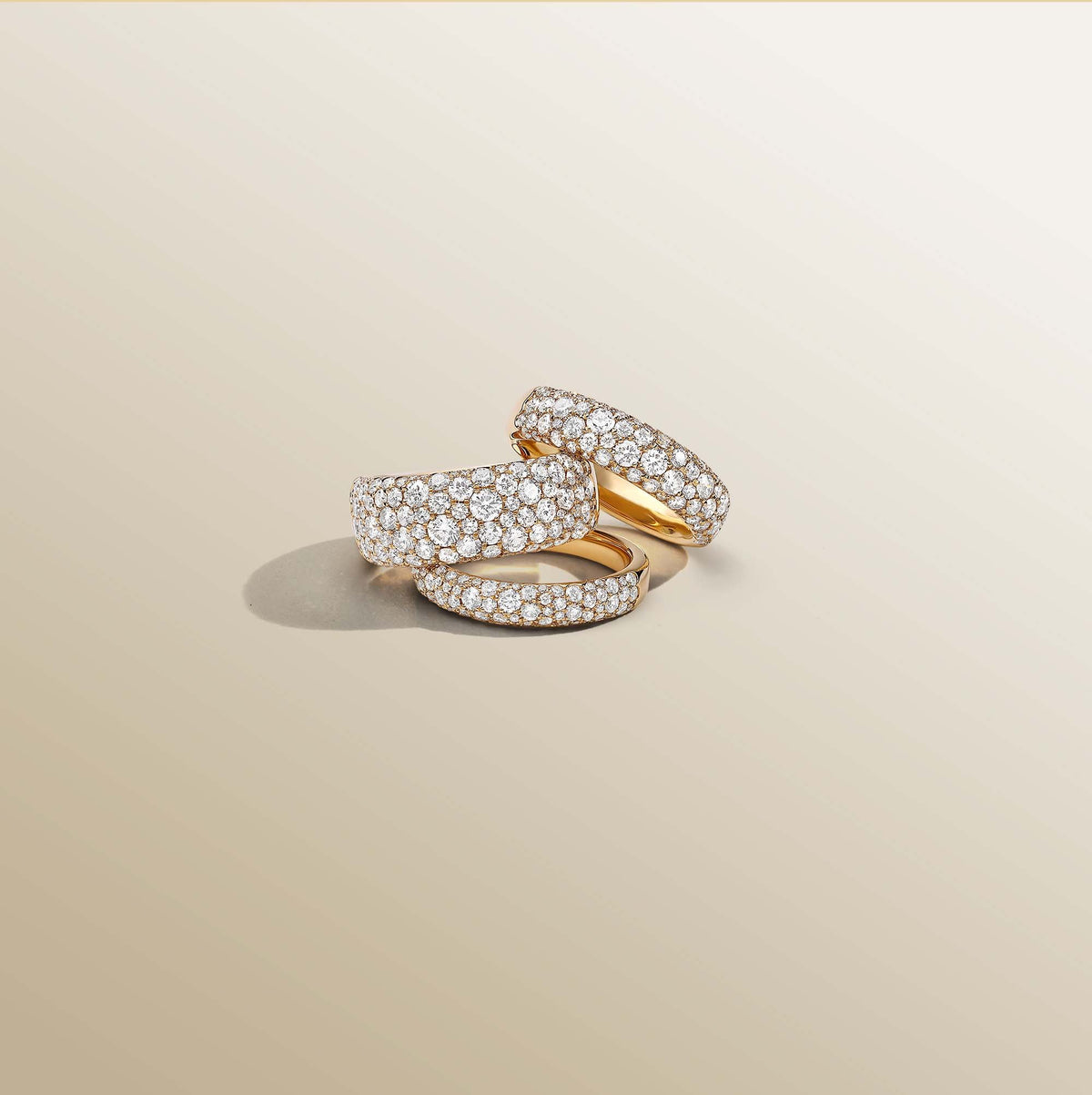 Three Luminous pavé diamond dome rings in yellow, white and rose gold on a cream background