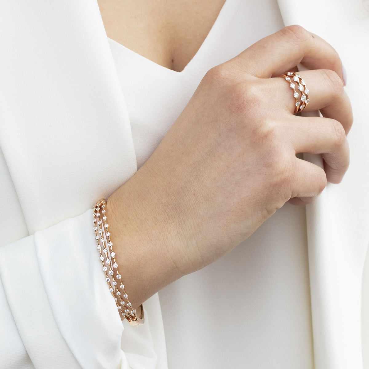 Woman in a white suit wearing a rose gold Wave diamond ring and matching bracelet